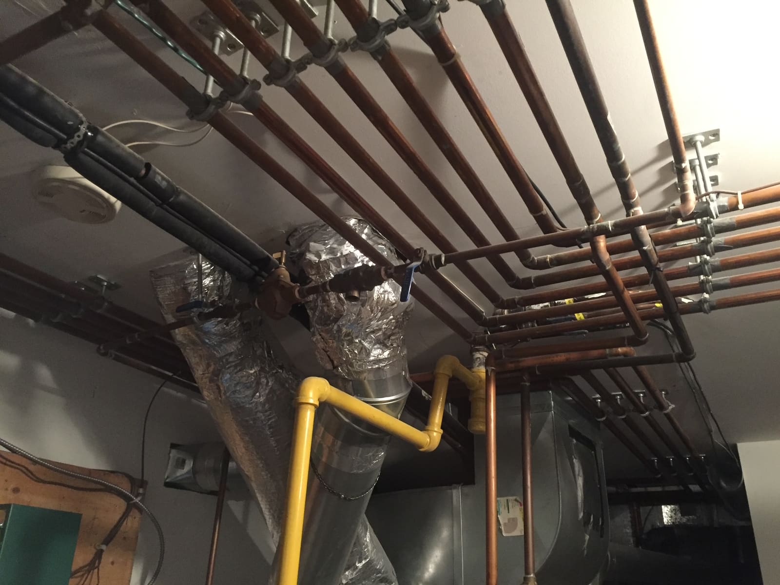 Copper and gas lines run overhead in a residential mechanical room by Glen The Plumber