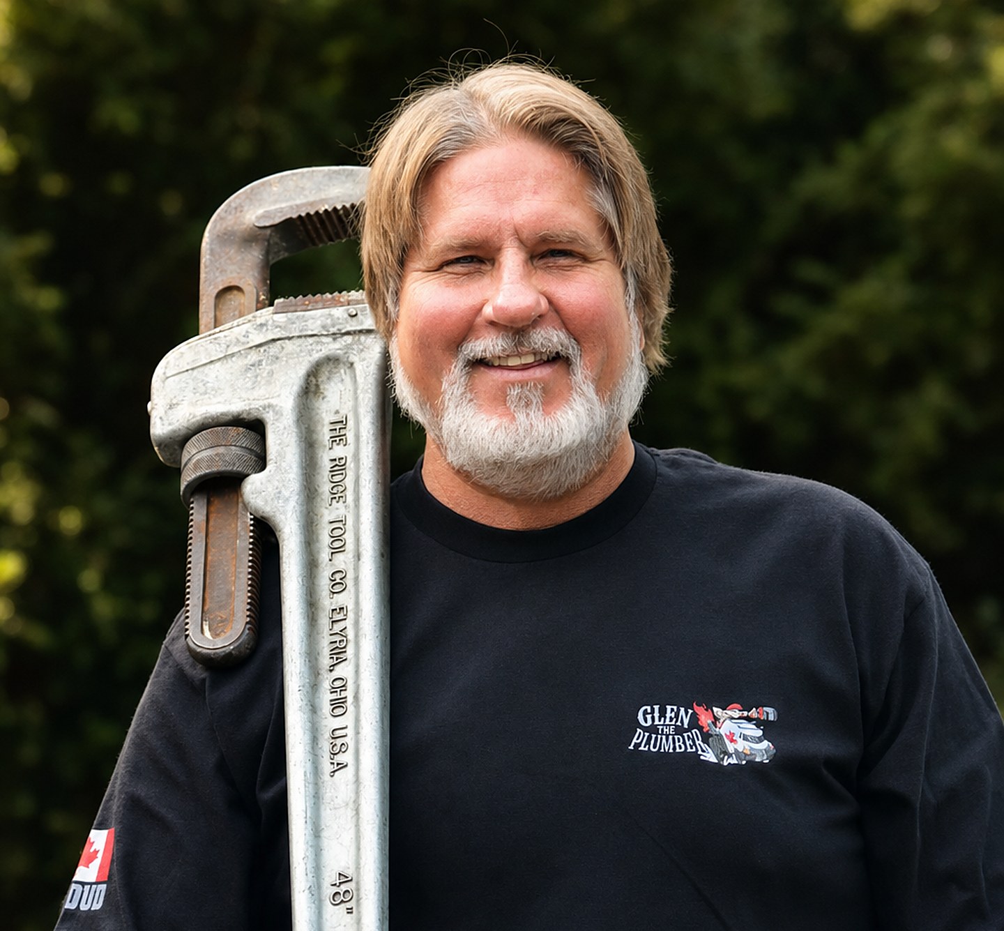 Glen Rescorl, Master Plumber and owner of Glen The Plumber, smiling with a pipe wrench over his shoulder